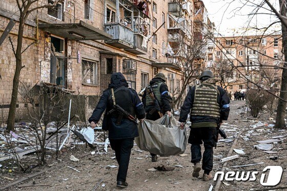 18일 (현지시간) 우크라이나 수도 키이우에서 러시아 군의 포격을 받아 파괴된 5층 아파트서 숨진 주민을 경찰이 옮기고 있다. © AFP=뉴스1 © News1 우동명 기자