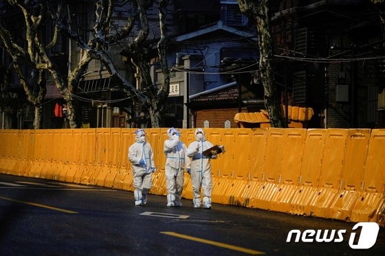 25일 코로나19가 대유행인 중국 상하이에서 개인보호장비(PPE)를 착용한 의료진들이 봉쇄된 지역의 장벽 앞을 걷고 있다. © 로이터=뉴스1 © News1 정수영 기자