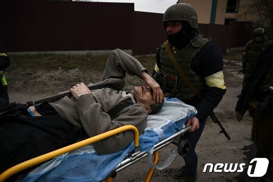7일(현지시간) 우크라이나 수도 키이우 인근 이르핀에서 러시아 군의 포격에 맞아 다리를 잃은 주민을 군인이 옮기고 있다. © AFP=뉴스1 © News1 우동명 기자