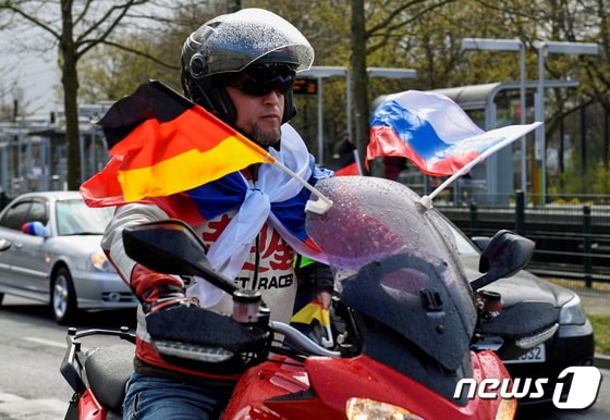 10일(현지시간) 독일 중부 하노버에서 한 러시아 남성이 자국과 독일 국기를 단 오토바이를 끌고 차량 시위에 참석하고 있다. © 로이터=뉴스1 © News1 정윤미 기자