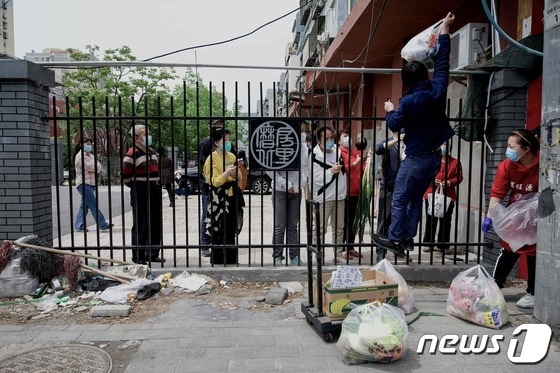 9일 (현지시간) 코로나19 봉쇄령이 내려진 중국 베이징의 주거 지역에서 배달원이 주민에게 물건을 전달하고 있다. © AFP=뉴스1 © News1 우동명 기자