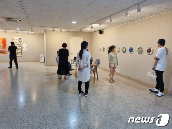 충주 관아골갤러리를 찾은 관람객들이 민비 작가의 '바다두꺼비' 시리즈를 감상하고 있다.(민비 작가 제공)2022.7.9/© 뉴스1
