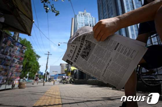 아베 신조 전 일본 총리가 선거 유세중 총에 맞고 숨진 다음날인 9일 중국 베이징에서 한 시민이 아베 전 총리의 피격 장면을 1면으로 장식한 신문들 들고 이동하고 있다. © AFP=뉴스1 © News1 이성철 기자