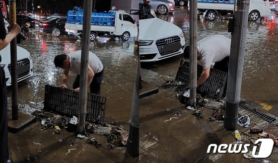 서울 강남역에서 맨손으로 배수구를 막은 쓰레기를 치우는 남성 시민. (온라인 커뮤니티 갈무리) © 뉴스1
