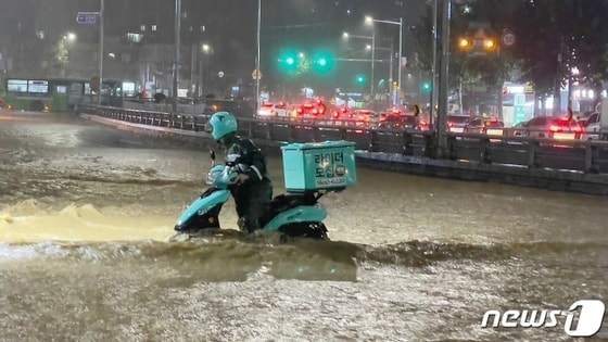 8월초 중부지방을 중심으로 폭우가 쏟아진 가운데 배달 라이더가 아슬아슬하게 물살을 헤치며 바이크를 옮기고 있다. 2022.8.8/뉴스1 ⓒ News1 김진환 기자 