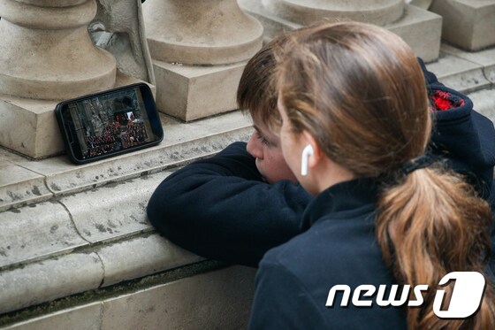 19일 오전(현지시간) 영국 런던 웨스트민스터 사원 인근에서 어린이들이 엘리자베스 2세 여왕 국장 생중계를 스마트폰으로 보고 있다. 2022.9.19/뉴스1 © News1 안은나 기자