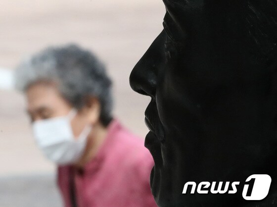 실외 마스크 착용 의무 전면 해제를 하루 앞둔 25일 서울 명동거리에서 흉상 앞으로 마스크 쓴 시민이 지나가고 있다. 2022.9.25/뉴스1 © News1 이성철 기자