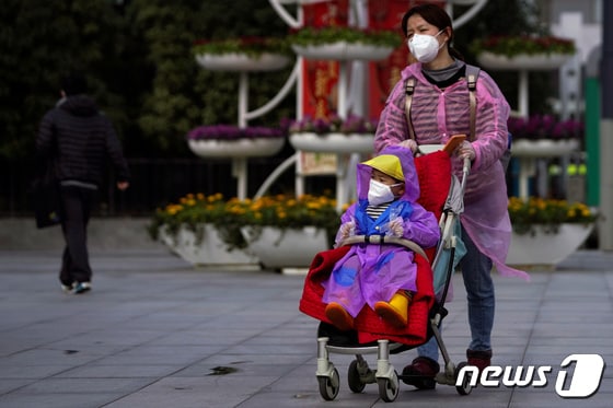 중국 상하이에서 한 여성이 아이와 마스크를 착용하며 길을 걷고 있다. 2020.02.13. © 로이터=뉴스1 © News1 정윤영 기자