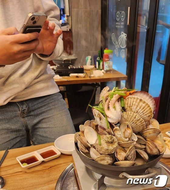 4일 오후 7시쯤 서울 관악구의 한 음식점에서 만난 김종희씨가 휴대전화로 음식 사진을 찍고 있는 모습. © 뉴스1 한병찬 기자
