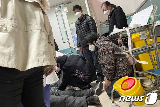 5일(현지시간) 중국 상하이에서 친척이 무릎을 꿇고 앉아 심폐소생술(CPR)을 받는 코로나19 감염자를 지켜보고 있다. © 로이터=뉴스1 © News1 권진영 기자