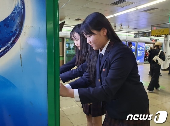 25일 부산 덕문중 학생들이 부산 도시철도 2호선 서면역 자판기에 점자를 붙이고 있다. 2023.10.25. © News1 DB 노경민 기자
