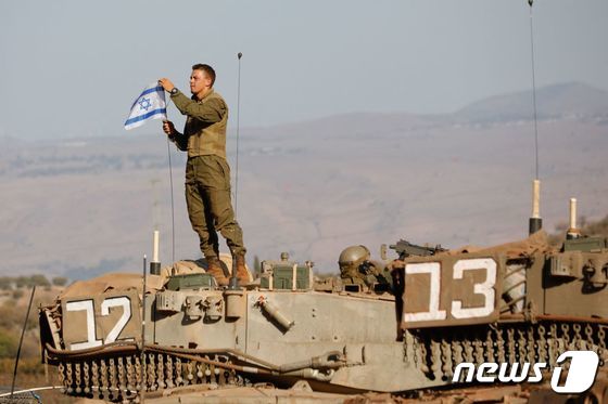 26일(현지시간) 이스라엘과 레바논 국경에서 한 이스라엘 군인이 '메르카바' 주력 전차 위에 올라가 국기를 정리하고 있다. 2023,10,27 © AFP=뉴스1 © News1 정지윤 기자