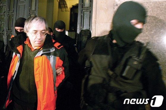2004년 4월1일 부쿠레슈티에서 촬영된 사진으로, 요가 종파인 미사(MISA)의 영적 지도자인 그레고리안 비볼라루(왼쪽)가 특수 경찰에 의해 법원에서 대피하는 모습이다.<자료사진> © AFP=뉴스1