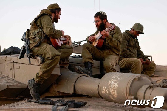 이스라엘군 병사들이 29일(현지시간) 가자지구와 이스라엘의 남부 접경지역에서 탱크에 올라가 기타를 연주하고 있다. 2023.11.30 © AFP=뉴스1 © News1 정지윤 기자