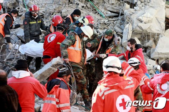 지난 9일 (현지시간) 규모 7.8의 강진이 강타한 시리아 자블레의 붕괴된 건물 잔해 아래에서 레바논 구조대원이 희생자를 들 것에 싣고 있다. © AFP=뉴스1 © News1 우동명 기자