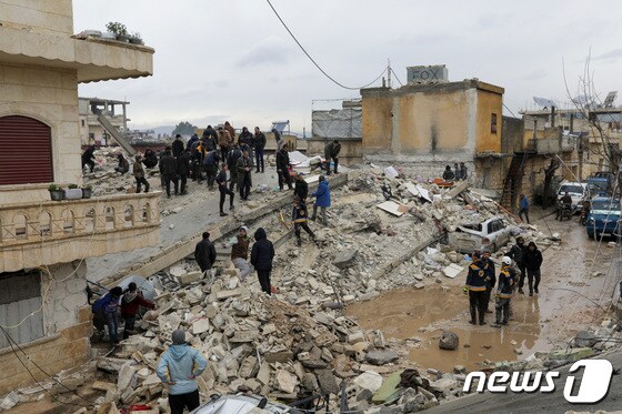 6일(현지시간) 시리아 잔다리스 마을에서 사람들이 지진으로 붕괴한 건물 잔해 속에서 희생자 및 생존자를 찾아 옮기고 있다. 강진 후 내린 비로 바닥엔 물이 가득 고였다. 시리아 정부는 통제 지역에서만 326명이 숨졌다고 발표했다. © 로이터=뉴스1 © News1 권진영 기자