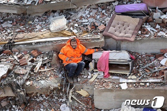 튀르키예 카라만마라슈의 건물 잔해에서 메수트 한제르라는 남성이 침대 위에서 죽은 딸의 손을 잡고 있다. © AFP=뉴스1