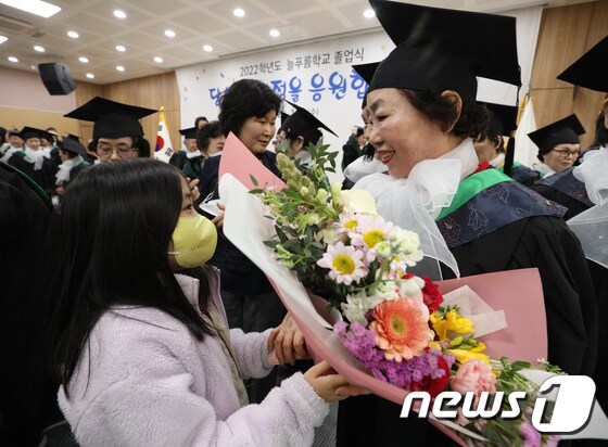 8일 서울 영등포구청 별관에서 열린 늘푸름학교 졸업식에서 졸업생이 손녀로부터 꽃다발을 받고 있다. 2023.2.8/뉴스1 © News1 신웅수 기자