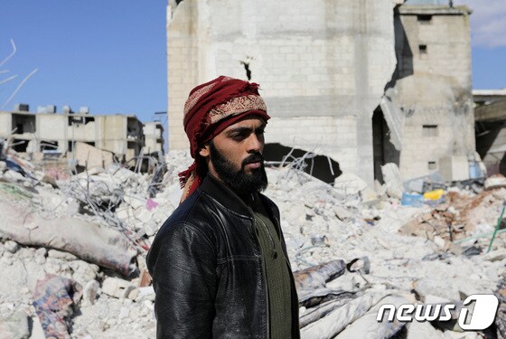 8일(현지시간) 시리아 잔다리스 마을에서 매형과 조카를 구한 살라 알하지 알 아캅이 잔해더미를 바라보고 있다. 그는 대지진으로 누나와 어린 조카를 잃었다. © 로이터=뉴스1 © News1 권진영 기자