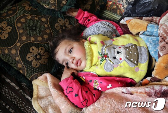 8일(현지시간) 시리아 잔다리스 마을의 붕괴 현장에서 살아남은 압둘라만 알리 알마무드의 막내 딸. 아이와 아버지는 막대기와 담요로 얼기설기 만든 임시 대피소로 몸을 피했다. © 로이터=뉴스1 © News1 권진영 기자