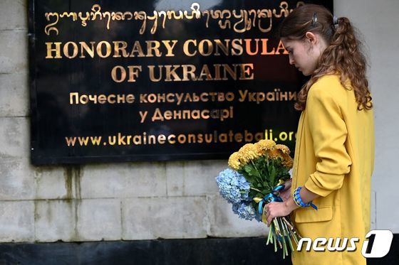 2월24일(현지시간) 인도네시아의 휴양지 발리 덴파사르에서 한 여성이 러시아의 침공 1년을 맞아 우크라이나 영사관 앞에 헌화하고 있다. 2023.02.24/뉴스1 © AFP=뉴스1 © News1 김민수 기자