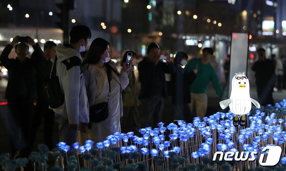 30일 오후 서울 종로구 광화문광장에서 열린 '광화에서 빛; 나이다'를 찾은 시민들이 불 밝힌 LED 장미를 살펴보고 있다. 2023.3.30/뉴스1 © News1 김진환 기자