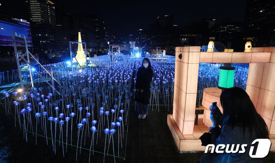 30일 오후 서울 종로구 광화문광장에서 열린 '광화에서 빛; 나이다'를 찾은 시민들이 불 밝힌 LED 장미를 배경으로 사진을 찍고 있다. 2023.3.30/뉴스1 © News1 김진환 기자