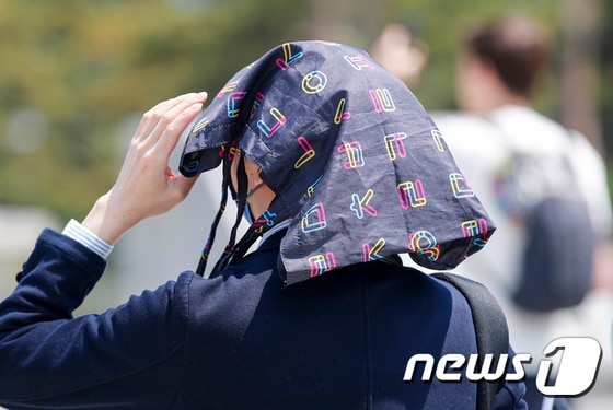 서울 시내 한 거리에서 시민이 햇빛을 막기 위해 손가방 머리에 올린 채 지나가고 있다. (사진은 기사 내용과 무관함) / 뉴스1 © News1