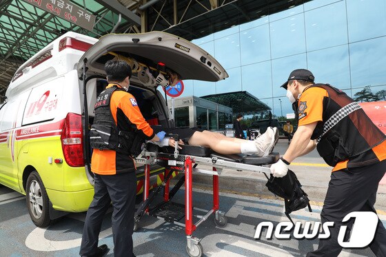 대구공항 도착 직후 고통을 호소하는 선수들을 119구조대가 병원으로 이송하기 위해 들것을 이용해 구급차로 옮기고 있다. 2023.5.26/뉴스1 © News1 공정식 기자