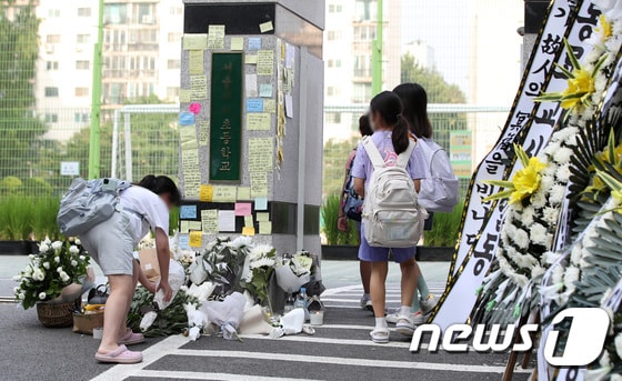 20일 오전 서울 서초구의 한 초등학교에서 학생이 정문에 꽃을 놓고 있다. 서울시교육청 등에 따르면, 지난 18일 오전 이 학교 1학년 담임인 A씨(23)가 극단적인 선택으로 사망하는 일이 발생했다. © News1 구윤성 기자
