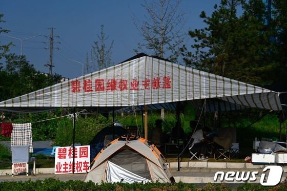 15일 베이징의 최근 디폴트 위기를 맞고 있는 컨트리 가든 공사 현장 옆에서 주민들이 항의 농성을 벌이고 있다. © AFP=뉴스1 