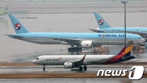 14일 오후 인천국제공항 계류장에 세워진 대한항공 항공기 앞으로 아시아나 항공기가 지나가고 있다. 2024.1.14/뉴스1 © News1 장수영 기자