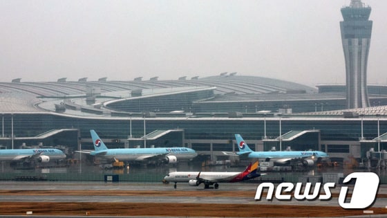 14일 오후 인천국제공항 계류장에 세워진 대한항공 항공기 앞으로 아시아나 항공기가 이륙하고 있다. 2024.1.14/뉴스1 © News1 장수영 기자