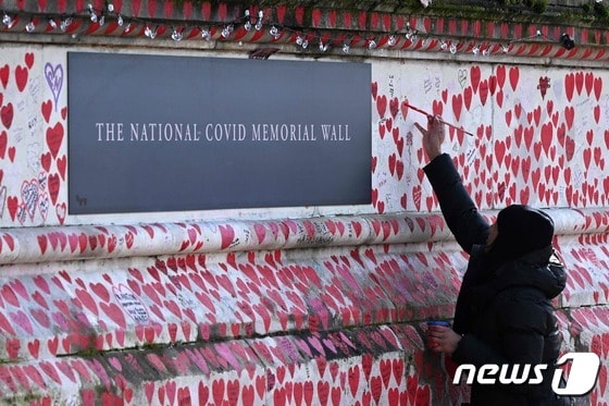 3일(현지시간) 코로나19로 목숨을 잃은 사람들을 기리는 영국 런던의 국립 코로나 기념 벽에 한 사람이 하트 모양을 그리고 있다. 2024.03.03 © AFP=뉴스1 © News1 정지윤 기자