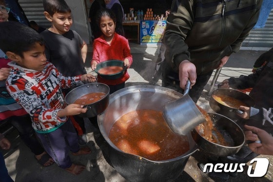 지난달 5일(현지시간) 가자지구 남부 라파에서 팔레스타인인 아동들이 그릇을 들고 음식을 나눠받고 있다. 이스라엘과 팔레스타인 무장 정파 하마스 간 전쟁으로 가자지구 아동들은 심각한 굶주림에 시달리고 있다. 2024.03.05/ © AFP=뉴스1 © News1 권진영 기자
