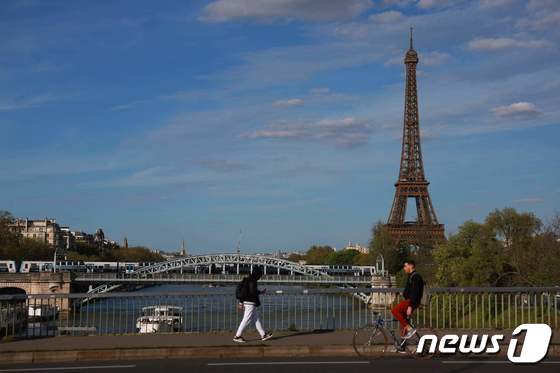 10일(현지시간) 파리 센강에서 한 보행자가 에펠탑을 배경으로 자전거를 타고 이동하고 있다. 2024.04.11 © AFP=뉴스1 © News1 조소영 기자