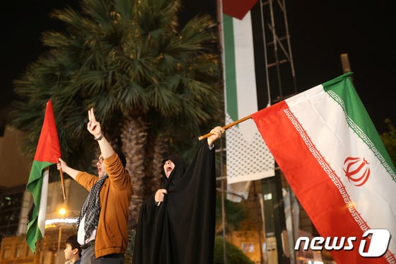 14일(현지시간) 이란이 이스라엘에 공습을 가한 이후 테헤란에서 이란인들이 거리로 나와 팔레스타인 깃발과 이란 국기를 흔들고 있다. 2024.04.14 © 로이터=뉴스1 © News1 정지윤 기자