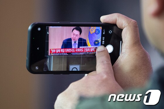 '국회와 긴밀히 협력' 윤 대통령 발언 휴대전화 담는 시민