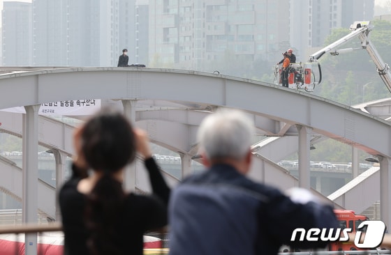 17일 오전 서울 한강대교 노량진 방면에서 신원을 알 수 없는 남성이 교량 위에 올라가 소동을 벌이고 있다. 2024.4.17/뉴스1 © News1 김도우 기자