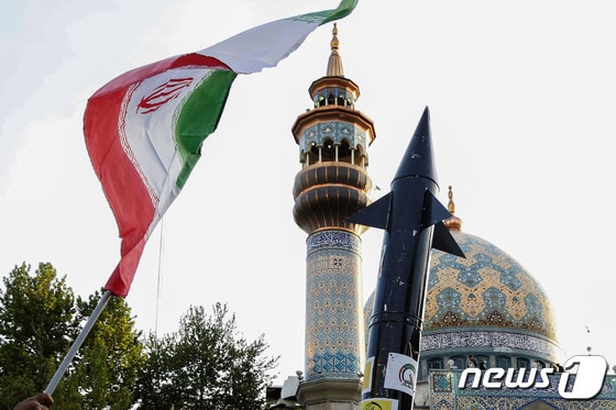 15일(현지시간) 이란 테헤란의 팔레스타인 광장에 사람들이 이란 국기와 미사일 모형을 들고 이스라엘에 대한 공습을 자축하는 모습. 2024.04.15 © AFP=뉴스1 © News1 정지윤 기자