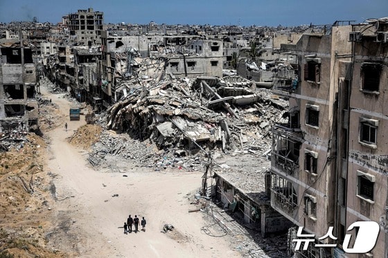22일 팔레스타인 남부 칸유니스 지역을 사람들이 걸어가고 있다. 6개월 이상 지속된 가자 전쟁으로 도시 건물들이 처참하게 훼손됐다. 2024.04.22 © AFP=뉴스1 © News1 최종일 기자