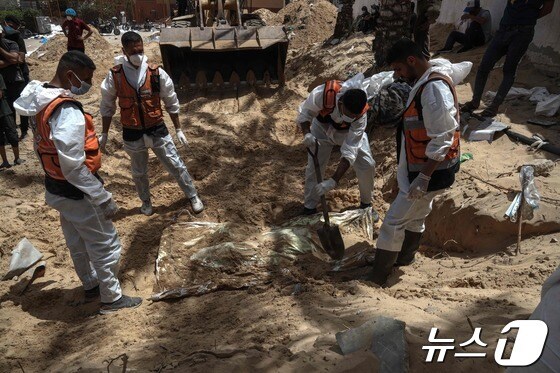 4월23일(현지시간) 보건 요원들이 가자지구 남부 칸 유니스의 나세르 의료단지에 매장된 시신들을 수습하고 있다. © AFP=뉴스1
