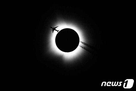 8일(현지시간) 인디애나 블루밍스턴 지역에서 한 비행기가 해를 품을 달을 지나가고 있다. © 로이터=뉴스1 © News1 박형기 기자