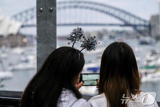 호주 시드니의 시드니 하버 브리지 앞에서 두 여성이 사진을 찍고 있다. 2023.12.31 © AFP=뉴스1 © News1 정지윤 기자