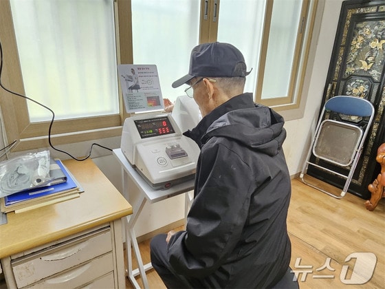 부산 기장군의 한 경로당을 방문한 노인이 혈압측정기를 사용하고 있다 (기장군청 제공)