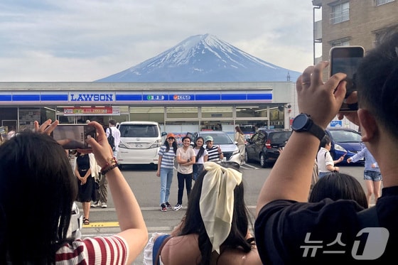 일본 야마나시현 후지카와구치코 마을의 한 편의점 앞에 후지산을 배경으로 사진을 찍으려는 관광객들이 몰려 있다. 2024.04.28/ © 로이터=뉴스1 © News1 권진영 기자
