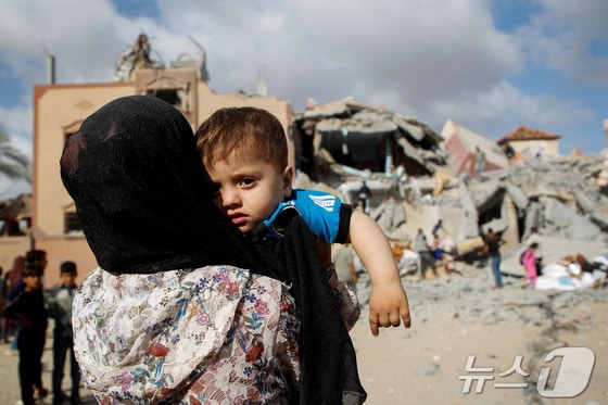 5일(현지시간) 가자지구 남부 라파에서 보호자 등에 업힌 한 어린이가 이스라엘의 주택 공습 현장을 바라보고 있다. 2024.05.05/ © 로이터=뉴스1 © News1 권진영 기자