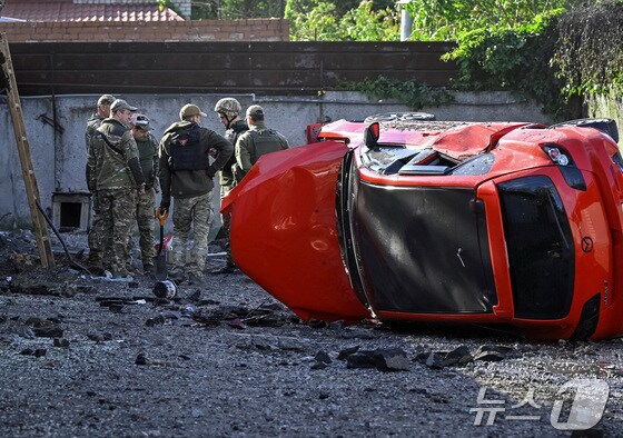 8일(현지시간) 우크라이나 자포리자에서 군경들이 러시아의 공격으로 뒤집어진 차를 바라보고 있다. 2024.05.08/ © 로이터=뉴스1 © News1 권진영 기자