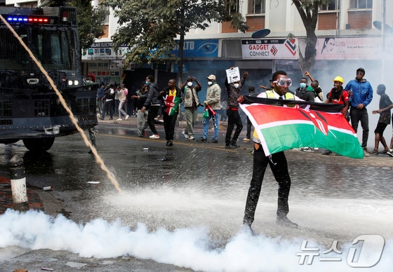 케냐 정부의 증세 정책에 반대하는 시민들이 25일(현지시간) 나이로비 거리로 나와 격렬한 시위를 벌이고 있다. 물대포와 최루탄을 사용하는 경찰 앞에서 케냐 국기를 흔드는 시민의 모습. 2024.06.25 © 로이터=뉴스1 © News1 임여익 기자